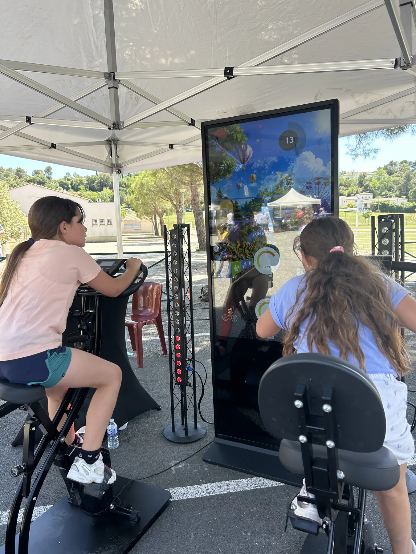 Stand VR sous tente avec écran de retour et participants autour